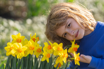 Fototapeta premium Spring fun for kids. Child play outdoors in a beautiful spring garden. Kid face in flowers. Adorable little kid in blooming cherry garden on beautiful spring day. Happy child during spring blossom.