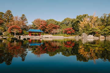 Obraz premium Wide Panoramic View of a Traditional Japanese Pavilion Reflected in a Still Garden Pond