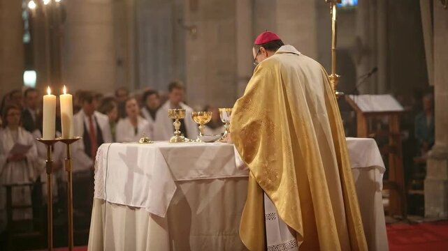 Priest in gold vestments celebrating mass at the altar with hands raised in prayer