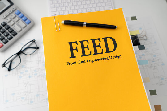 FEED front end engineering design document on office desk with technical drawings and engineering tools