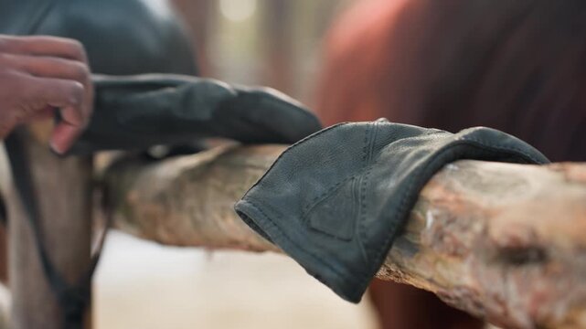 fencing gear scene, riding equipment and rustic setting, equestrian accessories displayed on weathered wooden surface, horse riding apparel and gear resting on aged wooden backdrop