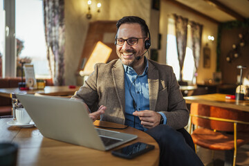 Fototapeta premium Businessman remote working during online video meeting in cafe