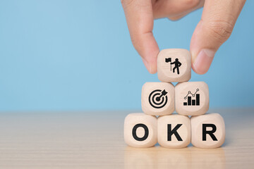 OKR Objectives, Key and Results wooden cube blocks on blue background. Business target and drive business and performance. Business and OKR - objectives and key results concept.