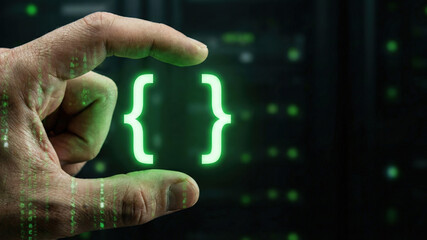 Green code bracket symbols held between fingers glowing in data center, futuristic programming concept with tense atmosphere