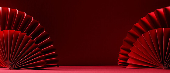 Naklejka premium Elegant oriental red paper fans on a red surface, traditional lunar new year festive background.