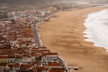 Aerial view of a coastal town with a sandy beach and ocean waves.