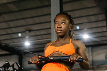 Determined woman exercising on rowing machine in gym