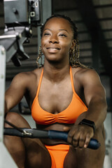 Black woman smiling while working out on rowing machine