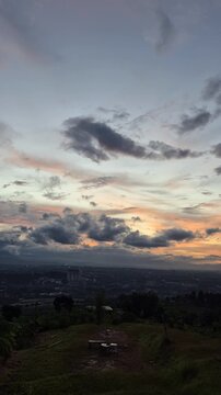 Timelapse of dramatic sunset clouds rolling over hills, shifting light and stormy skies creating a calm yet powerful landscape mood.
