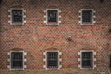 Vintage brickwork texture with symmetrical windows and iron security bars.