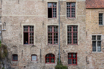 Weathered beige brick wall texture with multiple windows and visible drain pipe,Exterior of an old traditional house in Northern Europe with open windows