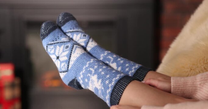 Woman putting on cozy socks at home, closeup