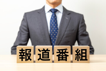 Obraz premium 「報道番組」と書かれたブロックとビジネスマン