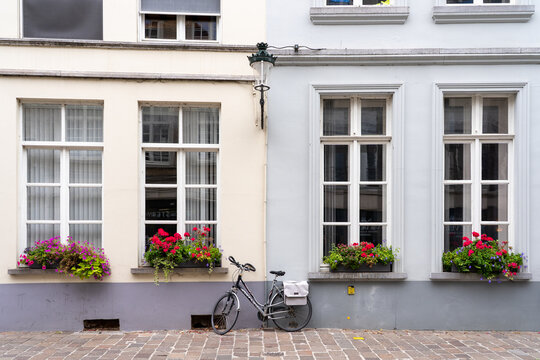 Charming European street facade with colorful flower boxes, sash windows, and a parked bicycle