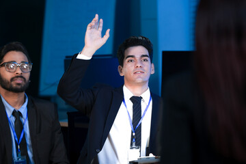 An Indian developer holds a tablet while a Caucasian engineer interacts with the screen. They are analyzing AI data or a cybersecurity system in a SOC.