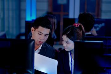 Deep dive into the code  Software engineers review system architecture or debug complex scripts together. Analyzing performance metrics on multiple screens in a dev hub at night.