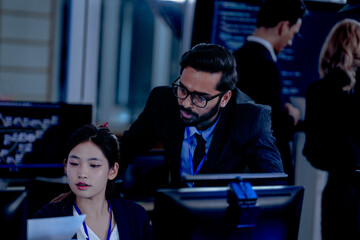 Obraz premium Intense collaboration hub Diverse AI team deep dive into project data late night. Manager guides Asian colleagues reviewing analytics for a new service launch in tech office.