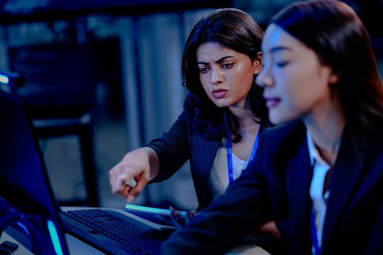 AI ethics review Female specialists collaborate late night, analyzing an AI model's performance data and code execution logs, ensuring responsible and fair deployment. - Powered by Adobe