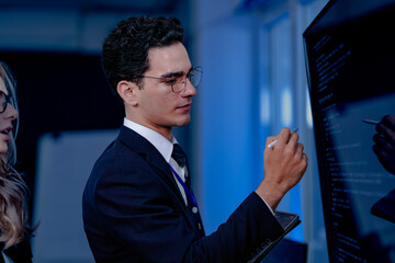 Code breakthrough achieved. Smiling senior developer points to a successful code segment on screen, sharing the solution with his colleague during a late night pair programming session.