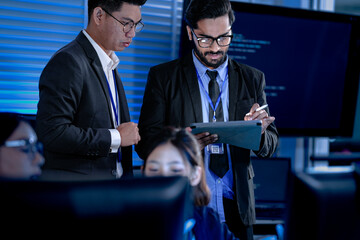 Lead developers analyze system architecture late night using tablet stylus pointing out details colleagues focused code visible screens debugging technical deep dive software build.