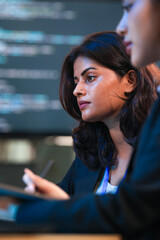 Code refinement power session. Focused female developers analyze complex script colleague points stylus critical logic fix discussed screen glows late night agile sprint push mode on now.