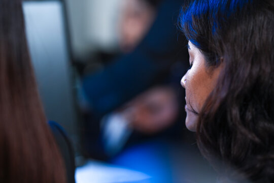 Profile view intense focus. Young female professional deeply absorbed work computer screen late night modern tech hub glow reflects determination concentration project deadline grind. - Powered by Adobe