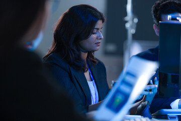 Monitoring AI training progress. Specialists oversee a machine learning model's training observing real time metrics on screen discussing adjustments via tablet interface late night.