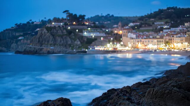 Seascape view of Tossa de Mar village at night with coastline and city lights. Travel, tourism, and beach concepts.
