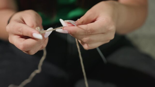 detailed stitching moment, intimate shot of detailed yarn crocheting with elegant nails, focused closeup of skillful hands crocheting textured yarn using needle and long white nails