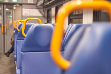 Close-up of empty train seats with blue upholstery and orange handles in modern public transit.