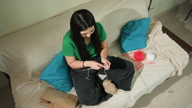 lady knitting relaxingly, person diligently crafting knitting samples during evening hours, individual focusing on knitting intricate pieces with yarn while seated on comfortable sofa in evening