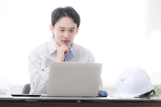 現場事務所で考える作業着の作業員　経営などの戦略を考える建築や製造業のポシティブイメージ