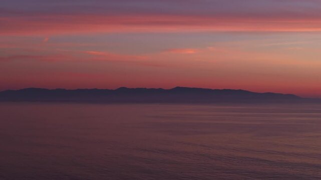 A beautiful and colorful ocean sunset as seen from Santa Cruz California looking over the pacific ocean towards Monterey California in a serene panning aerial drone shot