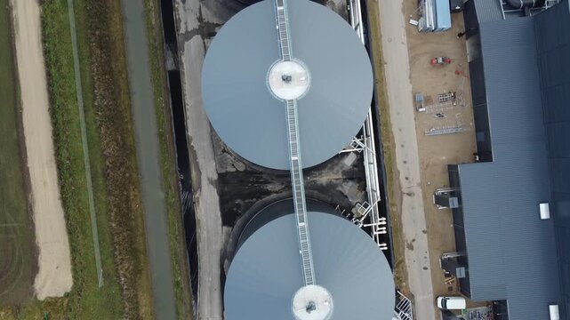 Drone footage of circular biogas digester and gas tanks at a renewable energy plant in rural Denmark, highlighting clean energy and industrial design.
