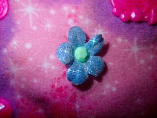 Close up of a craft flower with glitter sparkle on a pink purple background.