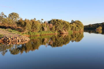 Calm stretch of the Burdekin River with trees reflected in the water in Charters Towers, Queensland, Australia