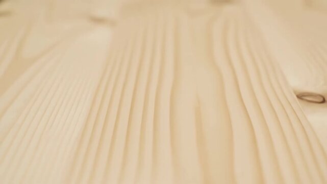 Close-up of light wooden surface with visible grain and knots, natural wood texture background.