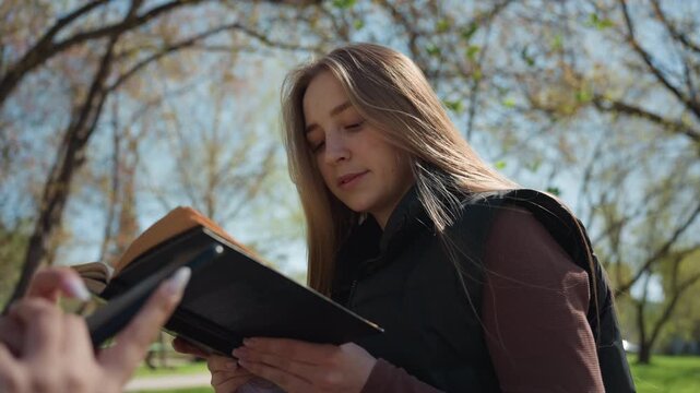 instructor reviews notes outdoors peacefully, educational professional examining materials in park, teacher and instructor engaged in study sessions within tranquil outdoor park setting for learning