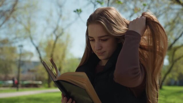 student reviewing outdoors, young woman of european descent revising notes beneath sunlit foliage, casual campus environment with focused young woman preparing for exams under sunny trees