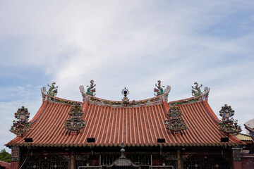 Ornate roof detail of Penang Kuan Yin Temple, featuring traditional Chinese architecture with dragon carvings and decorative ceramic ornaments under a clear sky.