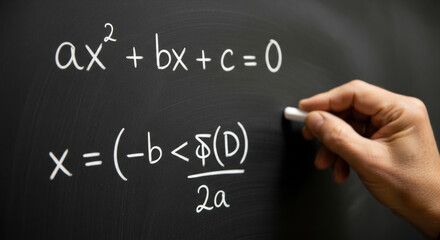 A close up of a blackboard with a quadratic equation written in white chalk, with a hand holding chalk. It depicts algebra and math problem solving skills.
