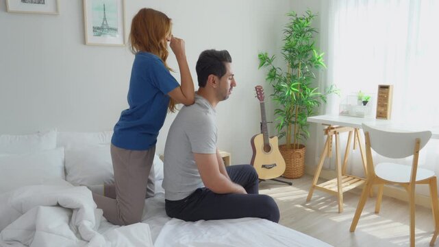 Caucasian husband getting back massage treatment from his wife at home. 
