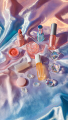 Flat lay of pastel beauty products on gradient silk fabric with dreamy tones and glowing highlights

