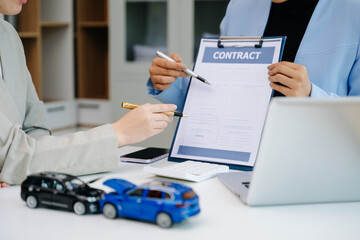 Car insurance contract signing with financial advisor. Customer reviewing agreement with car model on desk, representing auto insurance, finance, loan