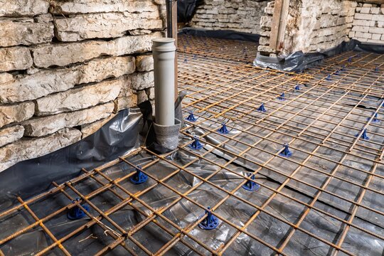 Preparing for concrete slab construction with reinforcement mesh and drainage pipe on a black membrane ensures a strong foundation. Professional building materials and engineering are essential.