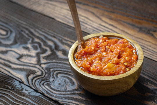 Freshly made Indonesian traditional chili sauce or sambal is placed in a small wooden bowl.