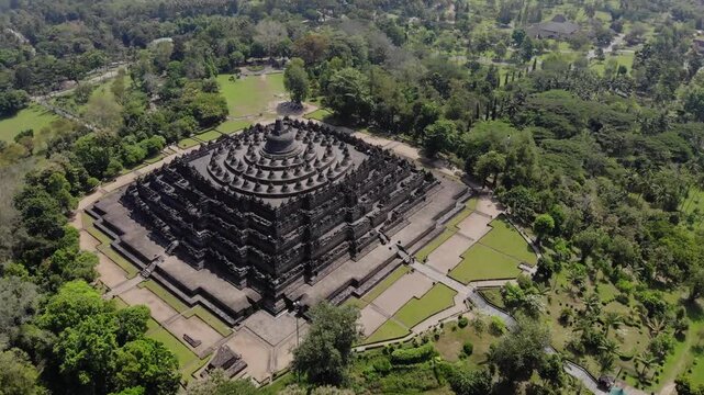 Aerial Dolly Track Zoom In of Borobudur Temple with Scenic Mountain Background Under Partly Cloudy Sky in 4K. Cinematic Medium aerial drone view of the Borobudur Temple in Indonesia.