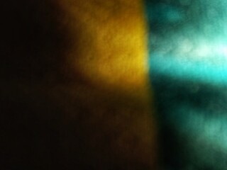 Abstract dark background with vibrant yellow and teal light glows