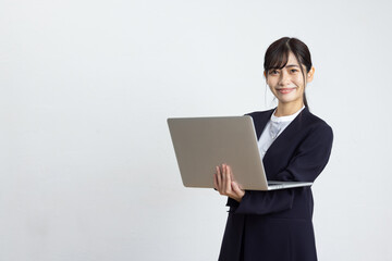 Young Businesswoman Using Laptop in Front of White Wall