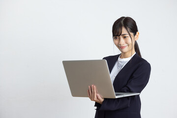 Young Businesswoman Using Laptop in Front of White Wall
